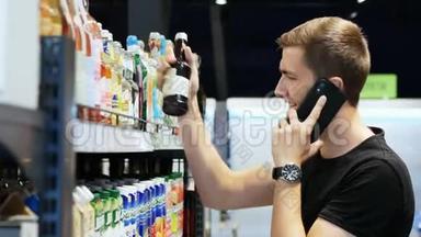快乐男人选择<strong>超市</strong>里的产品，用<strong>手机</strong>交谈，顾客选择货架上的商品